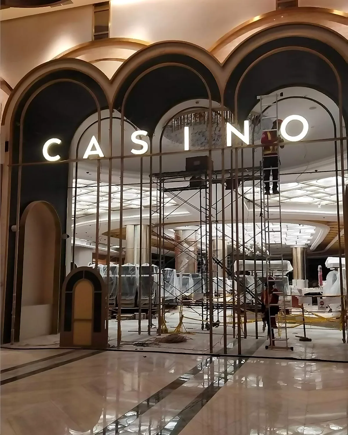 Illuminated CASINO sign above an arched entrance during the casino's fit-out, with scaffolding and covered machines inside